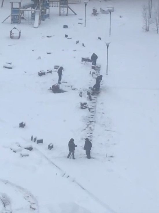 Рабочие в Новом Уренгое укладывают плитку поверх снега
