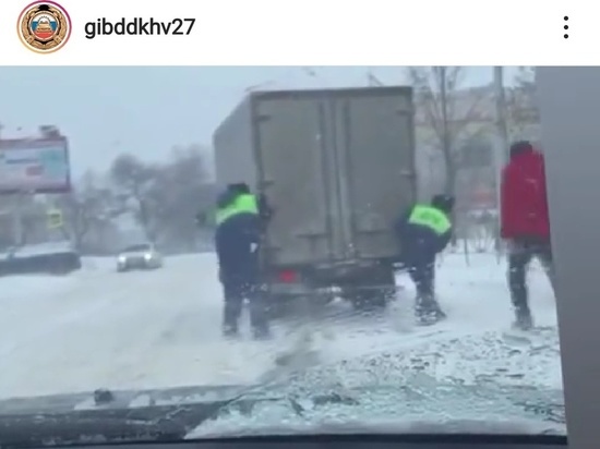 Сотрудники ГИБДД помогают выталкивать машины на заснеженных дорогах Хабаровска