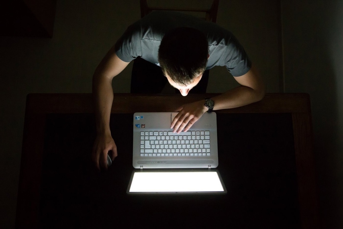 Человек сидит за компьютером ночью
