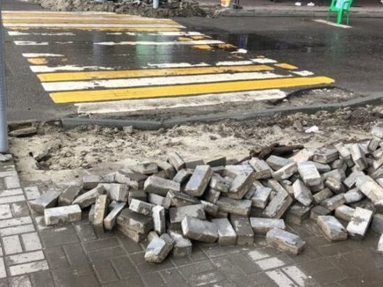В центре Ростова рабочие разворотили тротуар для ремонта и бросили его под дождем