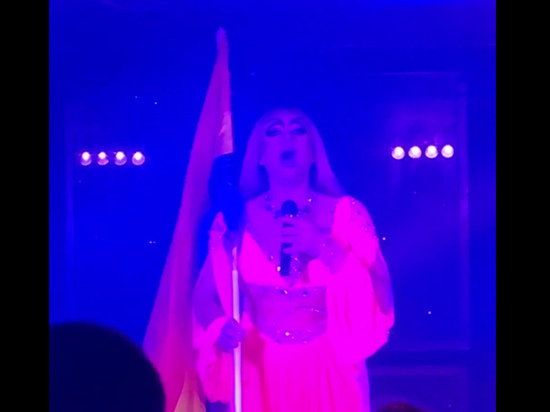Травести артист Сергей Нечаев (Бомба Киберсиси) исполнил в образе женщины гимн России с ЛГБТ-флагом в руках в екатеринбургском гей-клубе