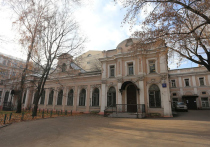 За доходными домами XIX века на старинном Покровском бульваре Москвы за оградами — два старинных здания, среди деревьев