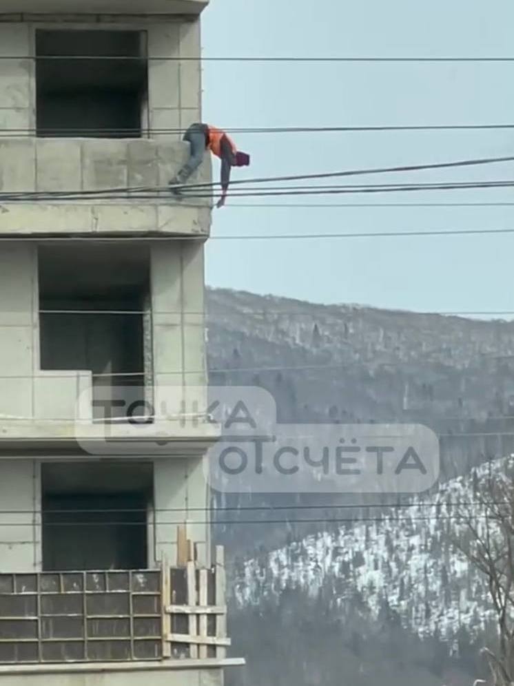Сахалинцы сняли на видео висящего на балконе без страховки строителя