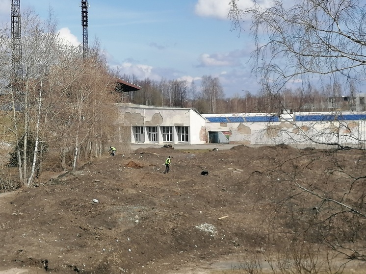 Рабочие выковыривают мусор из кучи грязи у стадиона Спартак в Петрозаводске