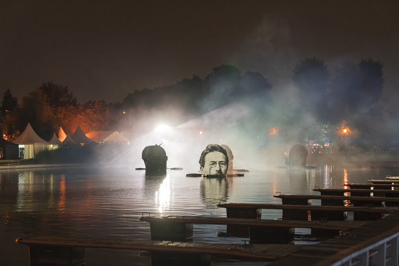 Actors in period costumes performing on a raft at night.
