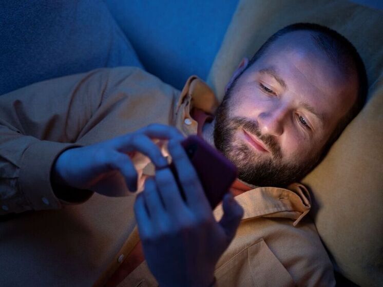 Человек смотрит в смартфон ночью в постели