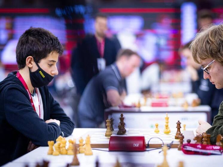 В Дохе, на фоне мирового шахматного праздника — чемпионата по блицу, — произошло событие, которое может стать поворотным моментом в новом поколении шахматистов. 12-летний российский вундеркинд Сергей Склокин одержал победу над действующим чемпионом мира по классическим шахматам, 19-летним индийцем Гукешем Доммараджу. Партия, в которой Склокин играл белыми фигурами, завершилась на 80-м ходу и стала демонстрацией зрелости, хладнокровия и тактической глубины, неожиданной для столь юного возраста.